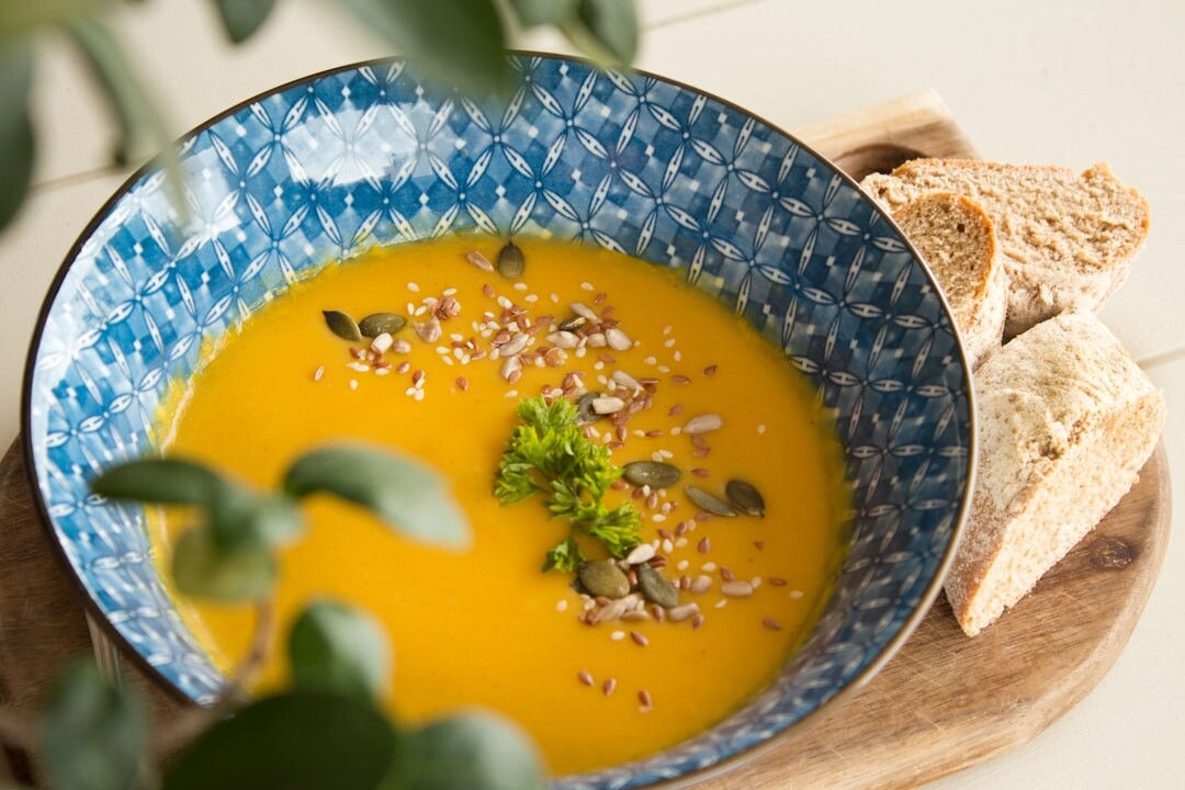 Bowl of warm autumn soup with pumpkin and herbs
